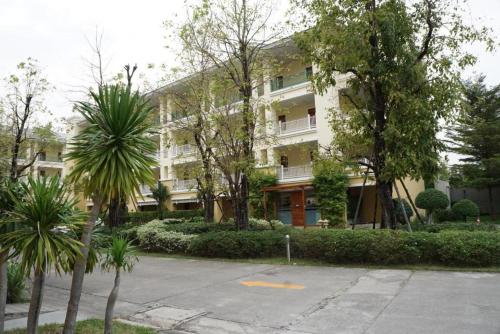 a large white building with trees in front of it at The One Residence Hotel in Bangkok