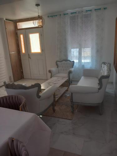 Elle comprend un salon doté d'un mobilier blanc et d'une fenêtre. dans l'établissement Résidence les jardins, à Romilly-sur-Seine