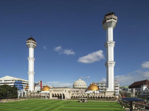 a mosque with two towers and a green field at Raffleshom Hotel in Bandung