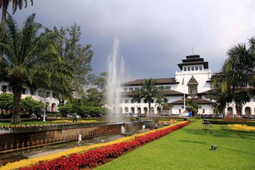a building with a fountain in the middle of a park at Raffleshom Hotel in Bandung