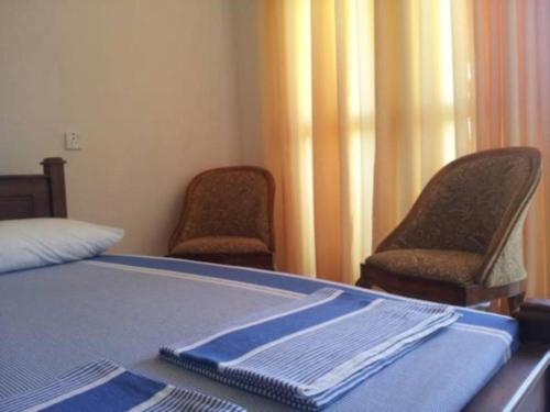 a bedroom with two chairs and a bed with a blue blanket at Dads Holiday Home in Matale
