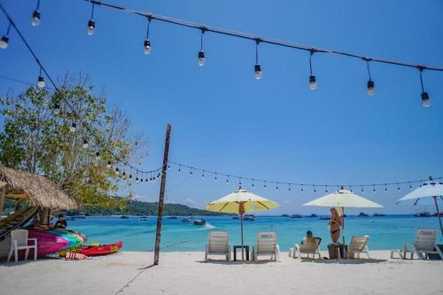 a beach with chairs and umbrellas on the beach at Phi Phi Nice Beach Hotel Hip in Phi Phi Don