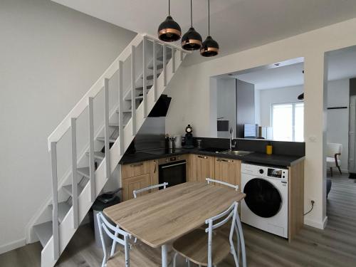 a kitchen with a wooden table and a staircase at Le Cosy du Centre - Proche plage et Port in Grand-Fort-Philippe