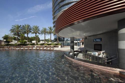 a swimming pool at a hotel with chairs and palm trees at City of Dreams - The Countdown Hotel in Macau