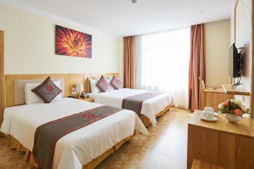 a hotel room with two beds and a television at Thai An Hotel in Cửa Lò
