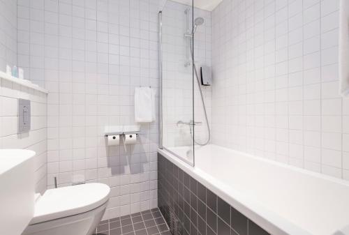 a bathroom with a tub and a toilet and a shower at Thon Hotel Rosenkrantz Bergen in Bergen