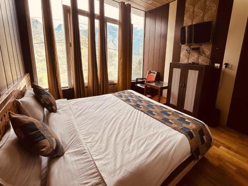 a bedroom with a large bed with a large window at Sleeping Beauty Hotel Moutain view property in Joshīmath