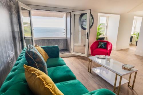 a living room with a green couch and a red chair at The Boat House Luxury Apartments Scarborough in Scarborough