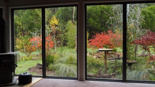a view of a garden through a sliding glass door at Blackwood Bush Retreat in Strathewen