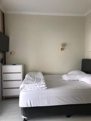 a bedroom with a bed with white sheets and a dresser at Bernice Homestay Syariah 1 Wonosobo in Wonosobo