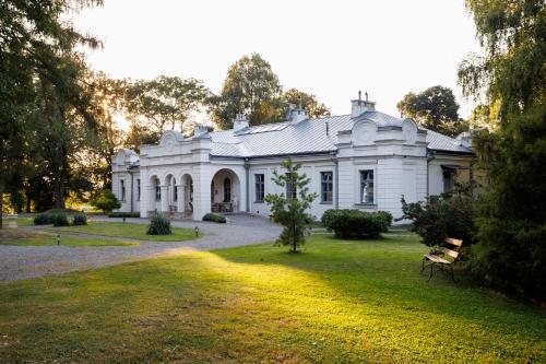 an old white house with a grass yard at Zamość Dwór Udrycze in Udrycze