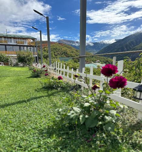 a white fence with flowers in the grass at Kurora e Gjelber Resort in Peshkopi