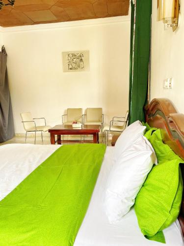 a bed with green sheets and a table and chairs at Pn meublés full option in Yaoundé