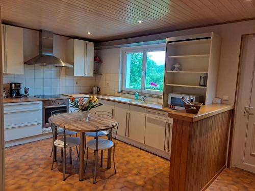 une cuisine avec une table et des chaises et une fenêtre dans l'établissement Maison La Roche du Miroir, à Plaimbois-du Miroir