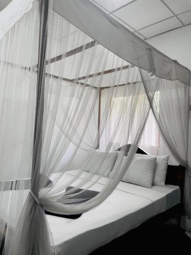 a bed with white drapes on top of it at SunFly Villa in Mirissa