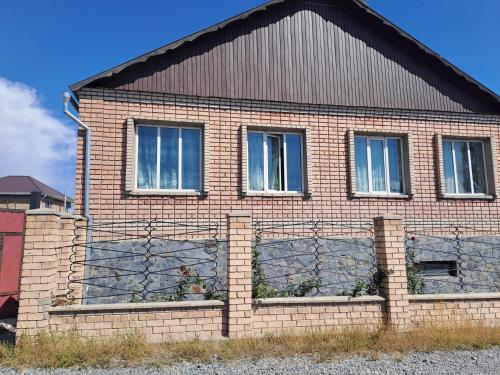 a brick house with three windows and a fence at Visit Balykchy in Balykchy