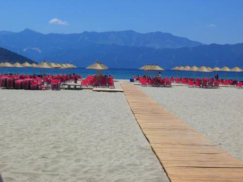 a wooden path on a beach with chairs and umbrellas at Astoria Keramoti Paralia beach in Keramotí