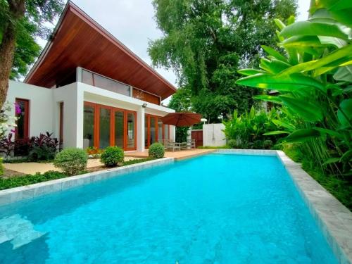 a villa with a swimming pool in front of a house at Pranaluxe 4 Bedroom Pool Villa C6 in Pran Buri