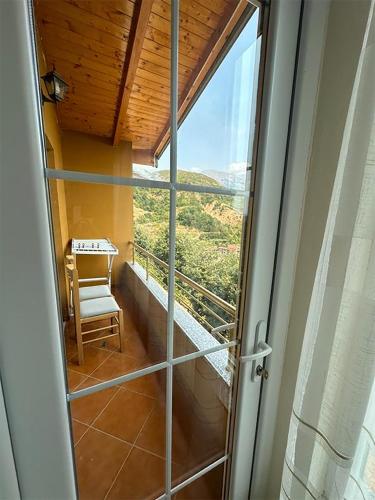 a room with a glass door with a table and a chair at Kurora e Gjelber Resort in Peshkopi