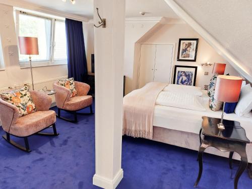 a bedroom with a bed and two chairs at Hotel Sir & Lady Astor in Düsseldorf