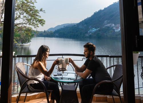 a man and woman sitting at a table with a view of a lake at The Lake Hill in Nainital