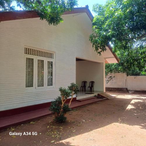 a white house with two chairs on the porch at Muthupalasa in Anuradhapura