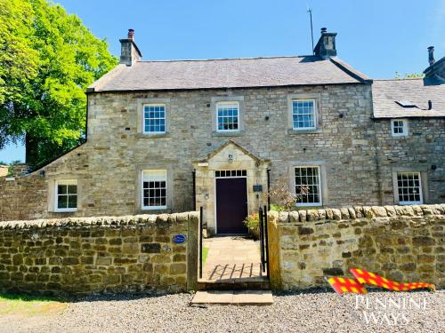 an old stone house with a fence in front of it at Bridge End House - Pet Friendly in Haltwhistle