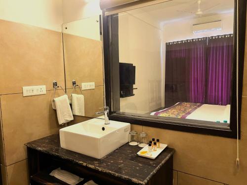 a bathroom with a sink and a mirror and a bed at The Lake Hill in Nainital