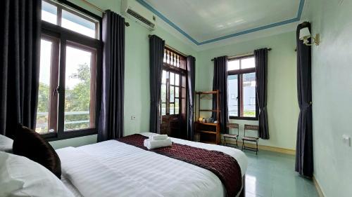 a bedroom with a large bed with windows at Vi TamCoc Hotel in Ninh Binh