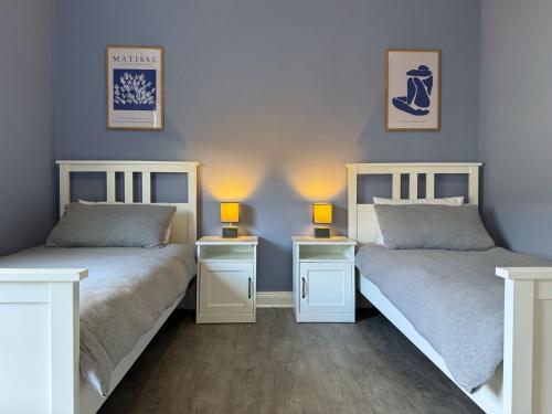 two beds in a room with two lamps at Modern Spacious 2 Bedroom House in Leigh, Free Parking in Leigh
