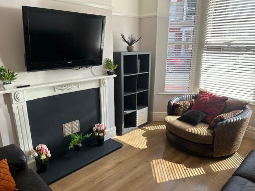 a living room with a fireplace with a flat screen tv at Entire Seaside Home 6 Private BedRooms Sleeps 10,4 Minute Walk To Station in New Brighton