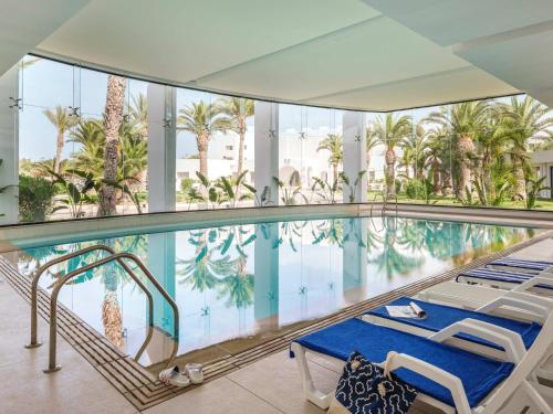 a swimming pool with palm trees in a building at TUI BLUE Palm Beach Hammamet - All inclusive in Hammamet