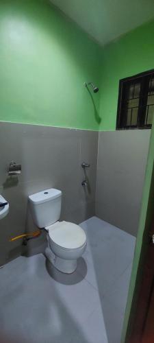 a bathroom with a white toilet and a window at La Villa Concha Housetel in Kabankalan