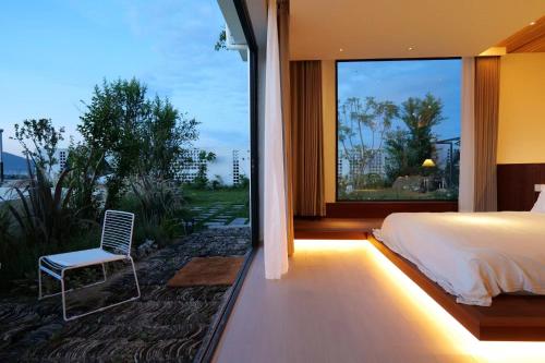 a bedroom with a bed and a chair and a large window at Kong Garden Designer Hotel in Dali Ancient Town