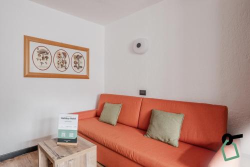 an orange couch in a living room with a table at Hotiday Apartments La Thuile in La Thuile