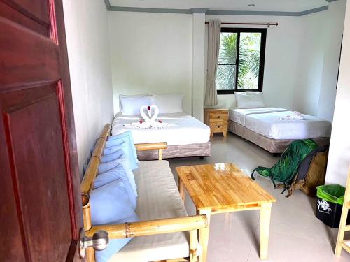 a small room with two beds and a table at TropiCoco Beach Resort Koh Phangan in Haad Yao