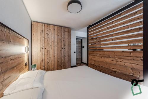 a bedroom with a large bed with a wooden wall at Hotiday Apartments La Thuile in La Thuile