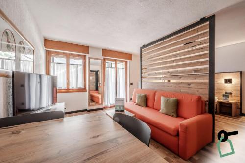 a living room with a red couch and a flat screen tv at Hotiday Apartments La Thuile in La Thuile