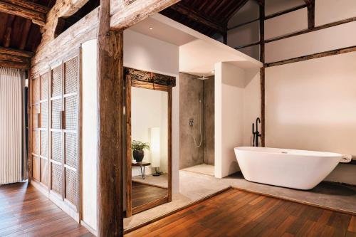 a bathroom with a white tub in a room with wooden ceilings at Kong Garden Designer Hotel in Dali Ancient Town