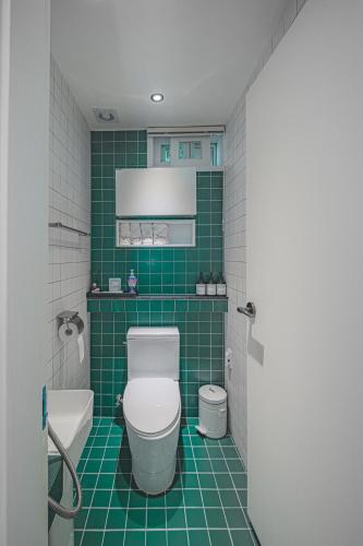 a green tiled bathroom with a toilet and a sink at Dongparang hanok stay in Gyeongju