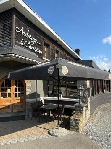 a restaurant with a table and an umbrella in front of it at Auberge du Carrefour Ch16 in Vielsalm