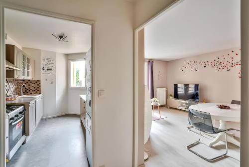 a white kitchen with a table and a counter top at Appartement familial proche métro in Créteil