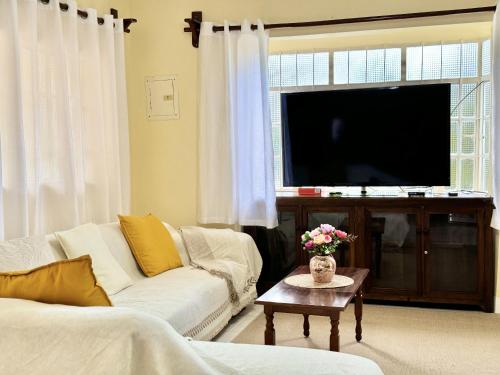 Una sala de estar con un sofá blanco y un televisor. en Cajigal Farmhouse - high speed converge internet and AC in 2 bedrooms, en Badoc