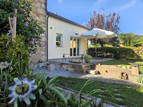 a house with an umbrella and a garden at La Bottega del Maniscalco in Filettole