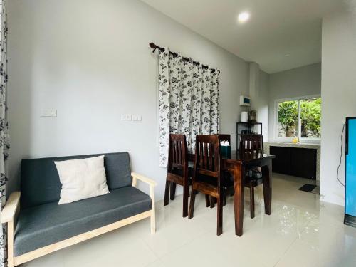 ein Wohnzimmer mit einer Couch und einem Tisch und Stühlen in der Unterkunft บ้าน2ห้องนอน1ห้องน้ำเงียบสงบเดิน10นาทีถึงชายหาด in Ban Khlong Haeng
