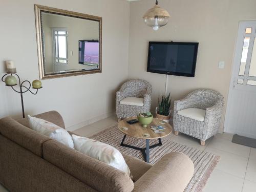 a living room with a couch and two chairs and a mirror at De Santa Villas in St Helena Bay