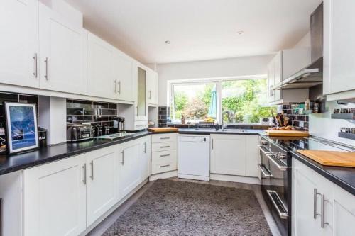 a kitchen with white cabinets and a large window at Very Large 5 Bed House Higham Ferrers family and contractors king beds Sky TV Pool Table Gym in Higham Ferrers
