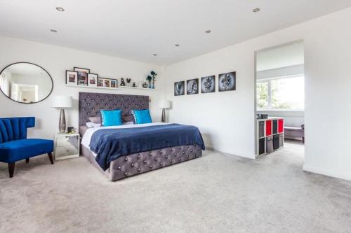 a bedroom with a large bed and a blue chair at Very Large 5 Bed House Higham Ferrers family and contractors king beds Sky TV Pool Table Gym in Higham Ferrers