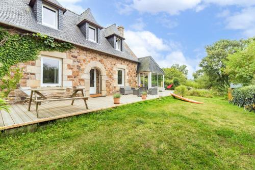 une maison avec une terrasse en bois dans la cour dans l'établissement Grande Maison, les pieds dans l'eau, Vacances Bord de Mer (50m de la plage)., à Penvénan
