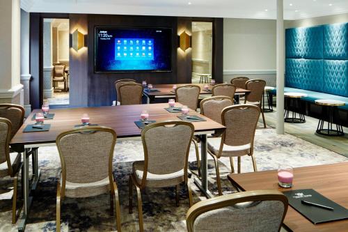 a dining room with tables and chairs and a tv at Hanbury Manor Marriott Hotel & Country Club in Ware
